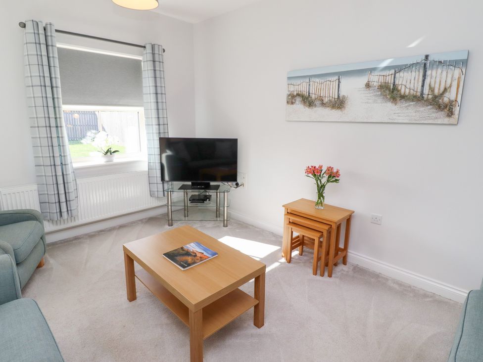 A living room with a television, sofa, and coffee table at The Haven in Embleton