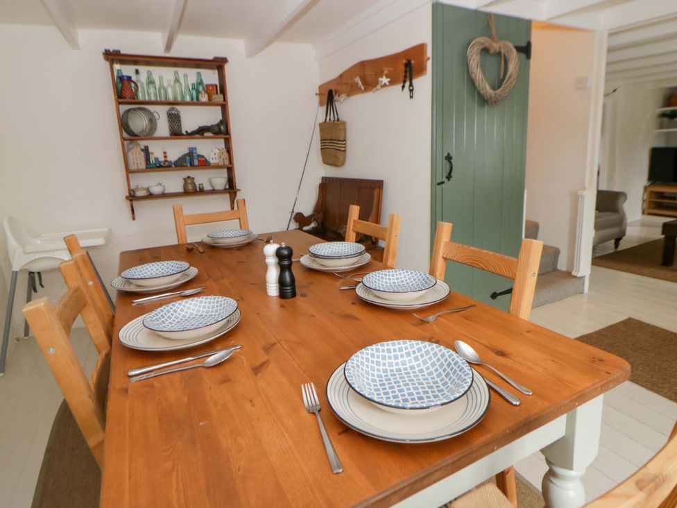 A dining room with a wooden table set for dinner at Fern Cottage in Aberporth