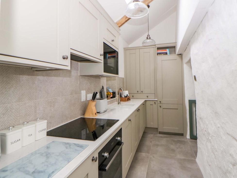 A kitchen with cabinets and appliances at Fern Cottage in Aberporth