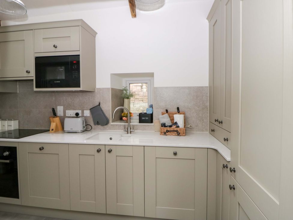 A kitchen with cabinets and appliances at Fern Cottage in Aberporth