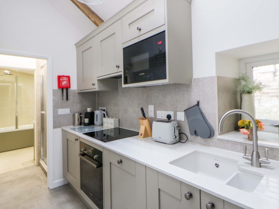 A kitchen with cabinets, stove, sink, and appliances at Fern Cottage in Aberporth