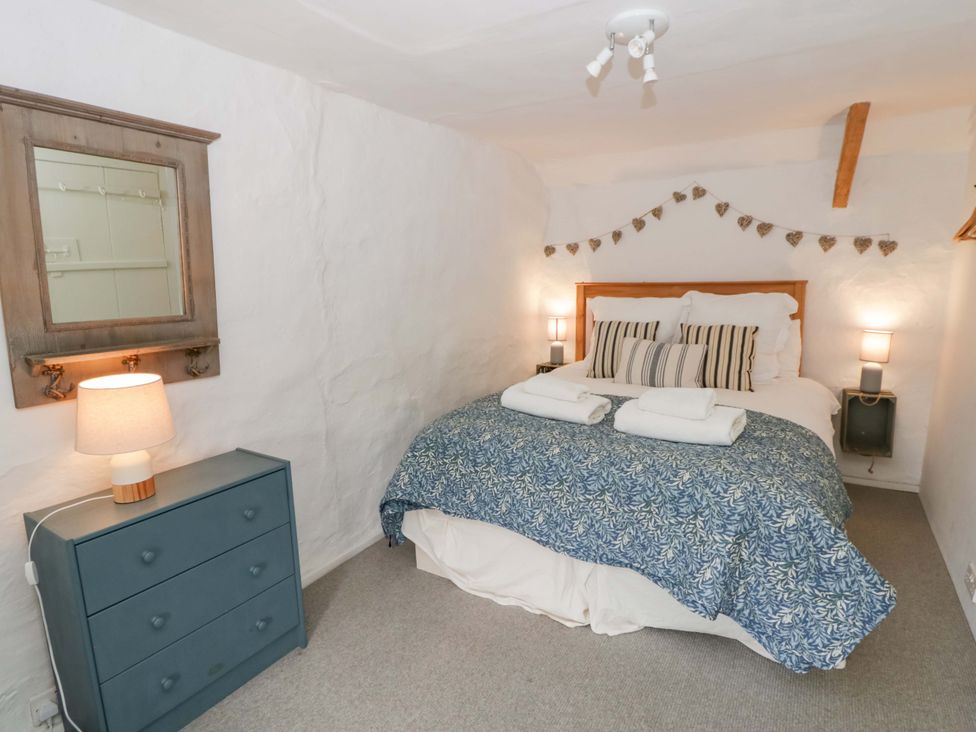 A bedroom with a bed and a dresser at Fern Cottage in Aberporth