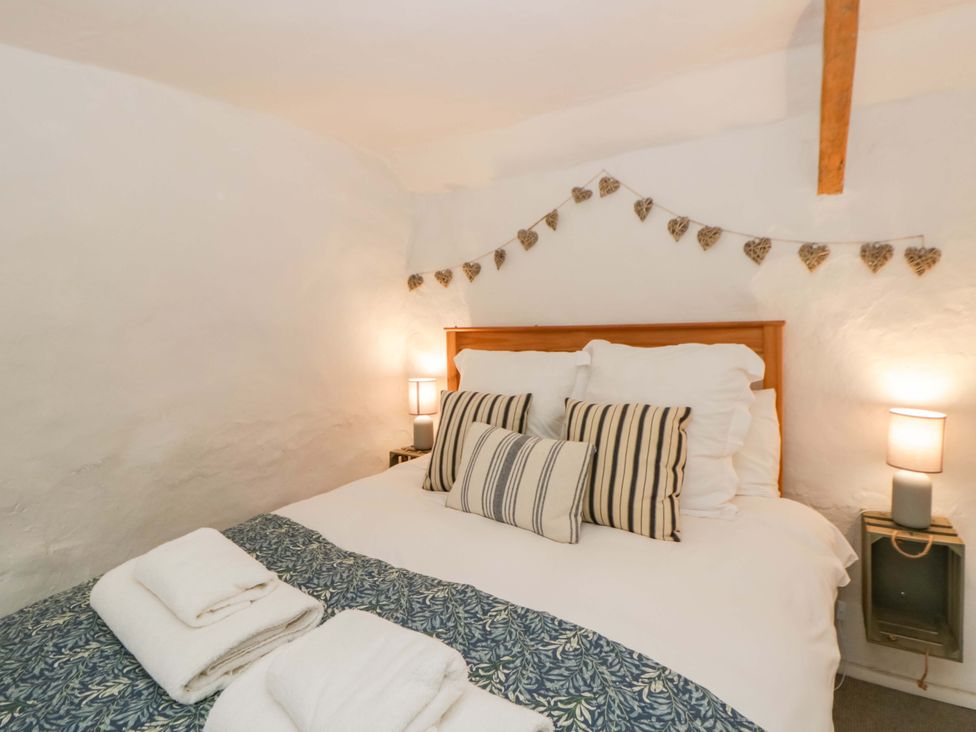 A bedroom with a bed and bedside lamps at Fern Cottage in Aberporth