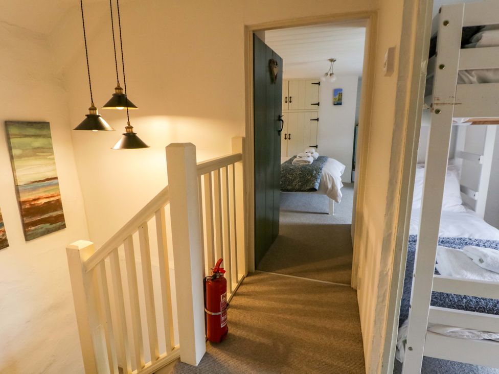 A hallway with a staircase and access to bedrooms at Fern Cottage in Aberporth