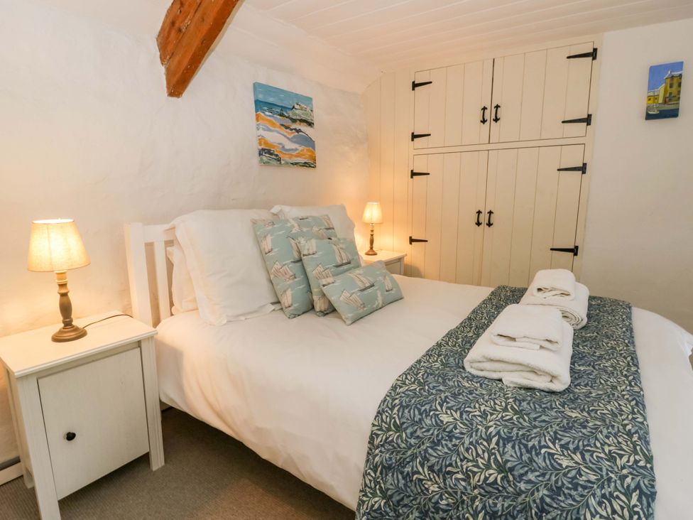 A bedroom with a bed and nightstand at Fern Cottage in Aberporth