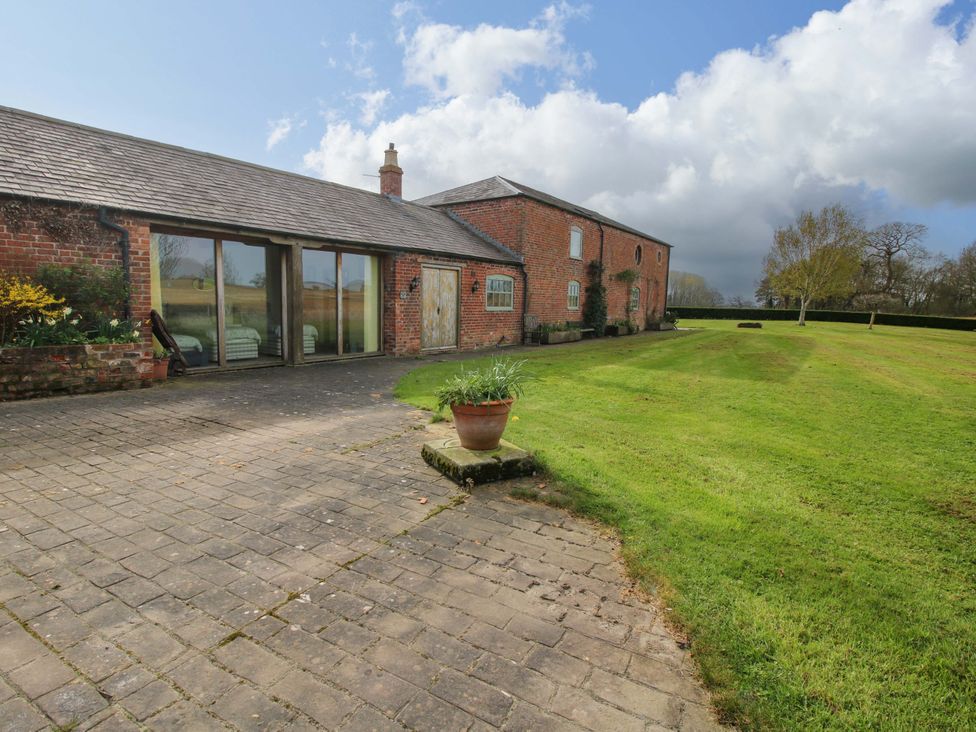 A brick building with windows and a door in a garden area at The Barn Cockshutt near Ellesmere