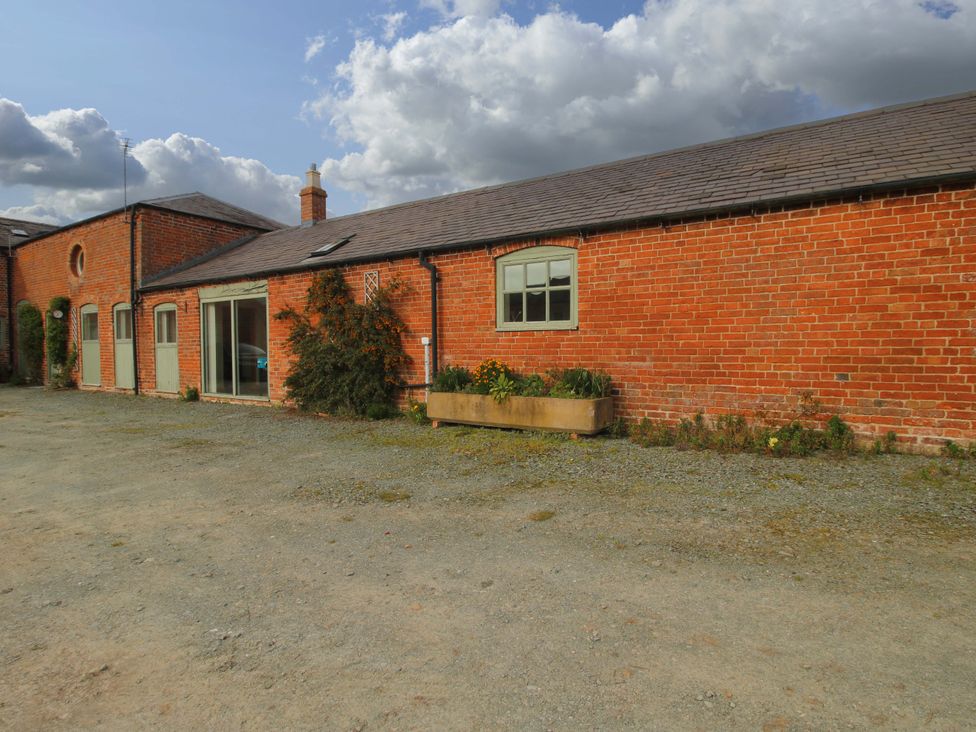 An outdoor view of a brick building with a planter at The Barn Cockshutt near Ellesmere