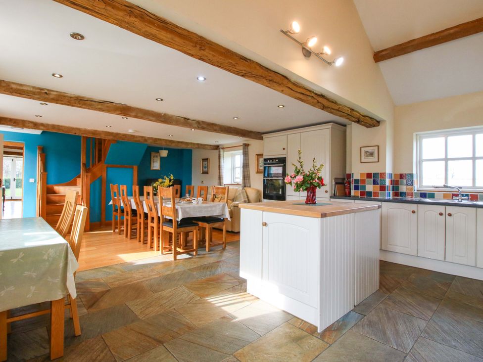 A kitchen with a dining area and staircase at The Barn Cockshutt near Ellesmere
