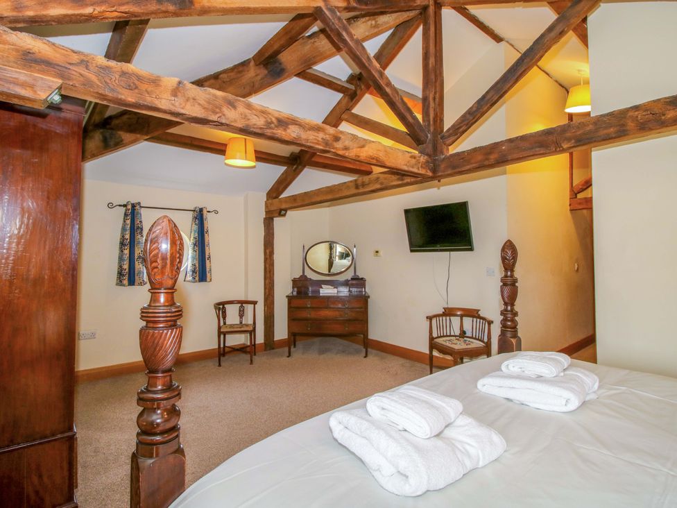 A bedroom with a bed and wooden furniture at The Barn in Cockshutt near Ellesmere