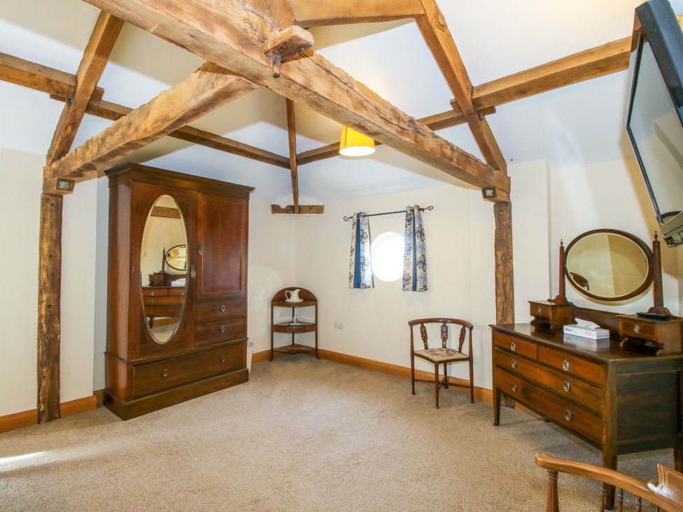 A bedroom with a dresser and a chair at The Barn in Cockshutt near Ellesmere