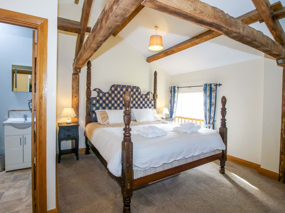 A bedroom with a four-poster bed and ensuite at The Barn in Cockshutt near Ellesmere