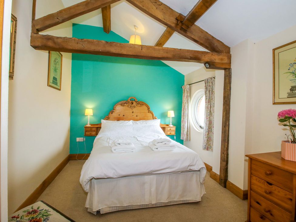 A bedroom with a bed and wooden furniture at The Barn in Cockshutt near Ellesmere