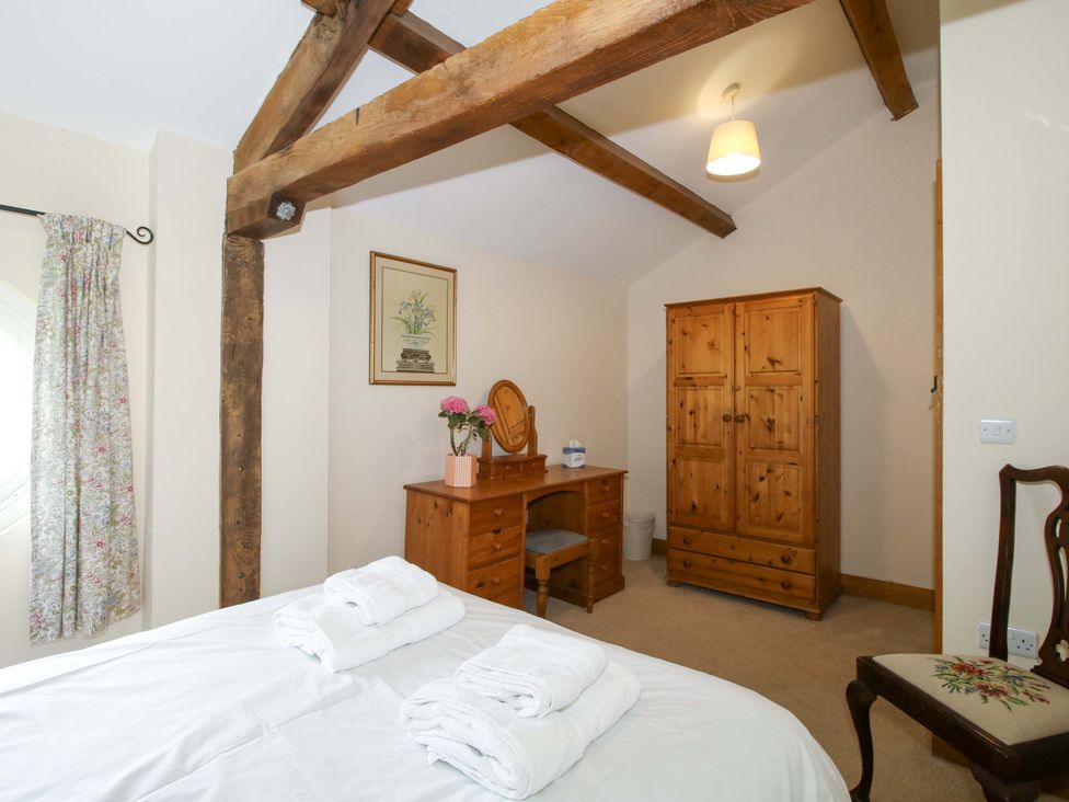 A bedroom with a bed, wardrobe, desk, and chair at The Barn Cockshutt near Ellesmere