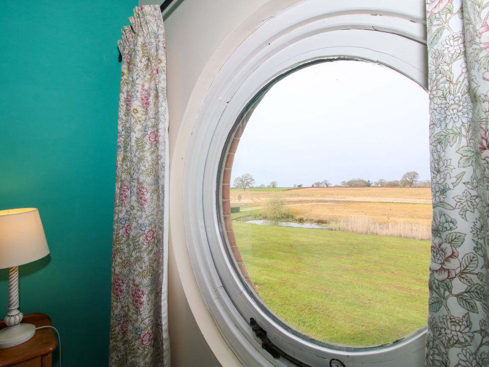 A room with a round window overlooking a grass landscape at The Barn Cockshutt near Ellesmere