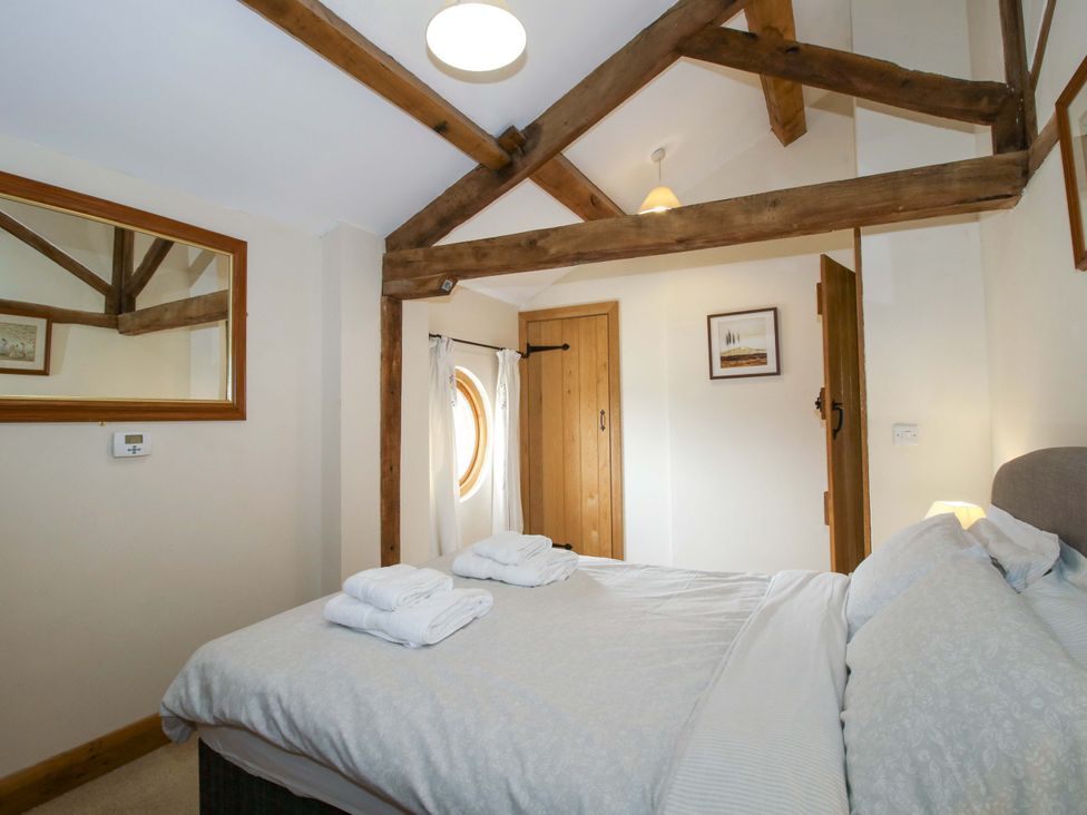 A bedroom with a bed and wooden beams at The Barn Cockshutt near Ellesmere