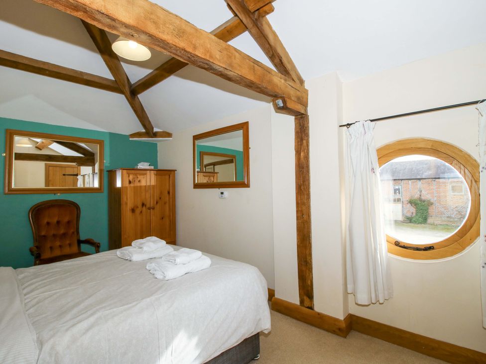 A bedroom with a bed and mirror at The Barn Cockshutt near Ellesmere
