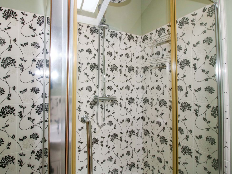A shower with floral tiles and a shelf at The Barn in Cockshutt near Ellesmere