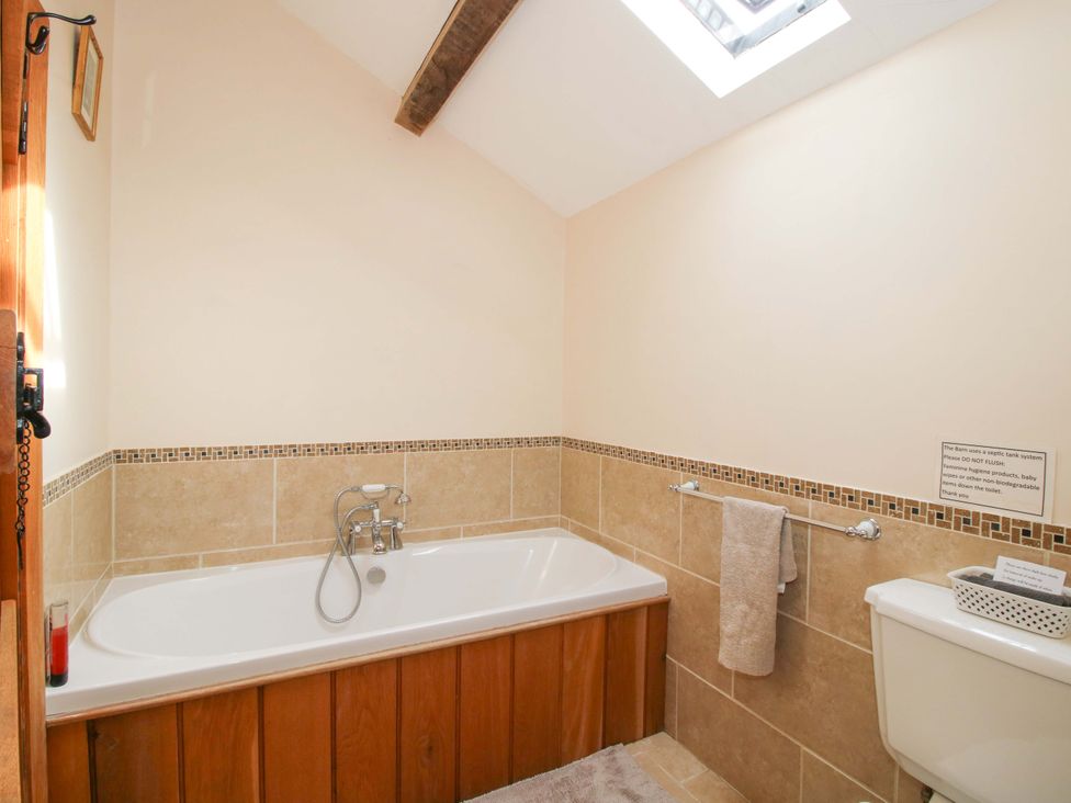 A bathroom with a bath tub, toilet, and towel rack at The Barn in Cockshutt near Ellesmere