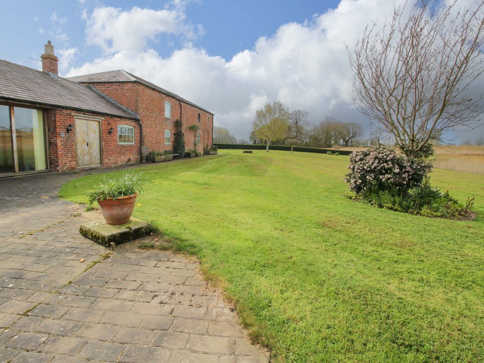An outdoor view of a garden and a brick building at The Barn Cockshutt near Ellesmere