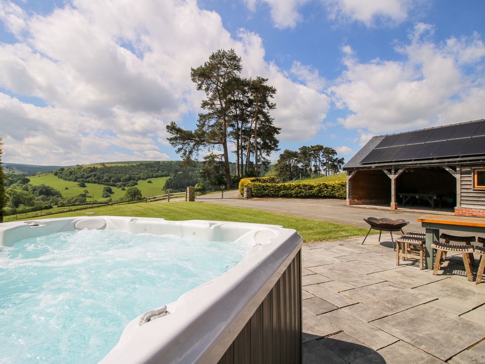 A hot tub with an outdoor table and chairs at The Hayloft Bleddfa near Knighton