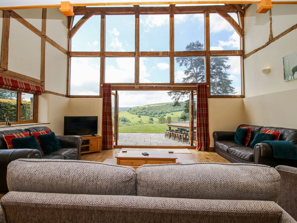 A living room with large windows and a sofa at The Hayloft in Bleddfa near Knighton