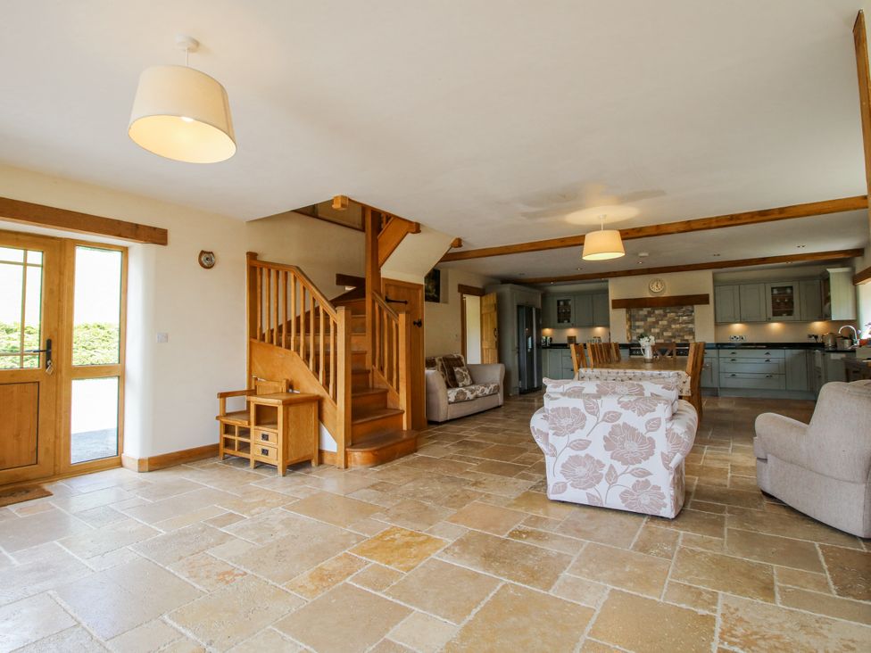 A living room with a staircase and dining table at The Hayloft in Bleddfa near Knighton