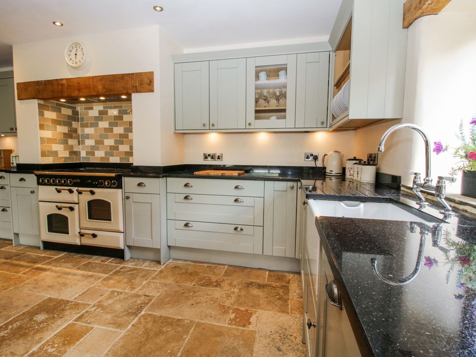 A kitchen with cabinets, sink, cooking range, and backsplash tiles at The Hayloft in Bleddfa near Knighton