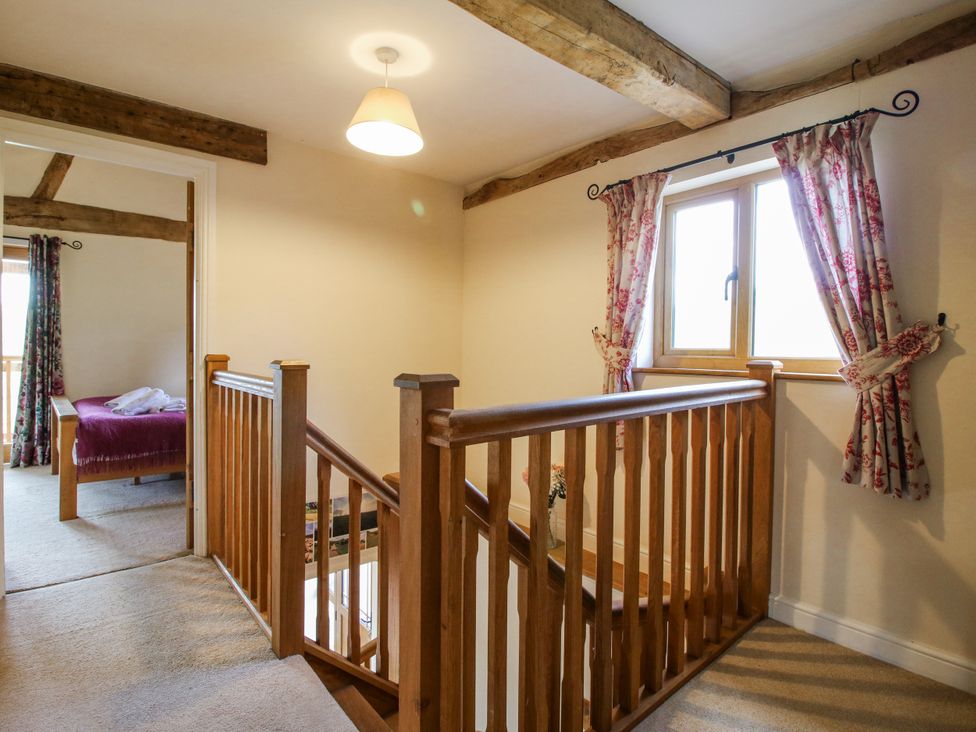 A landing with wooden stairs and a window at The Hayloft in Bleddfa near Knighton