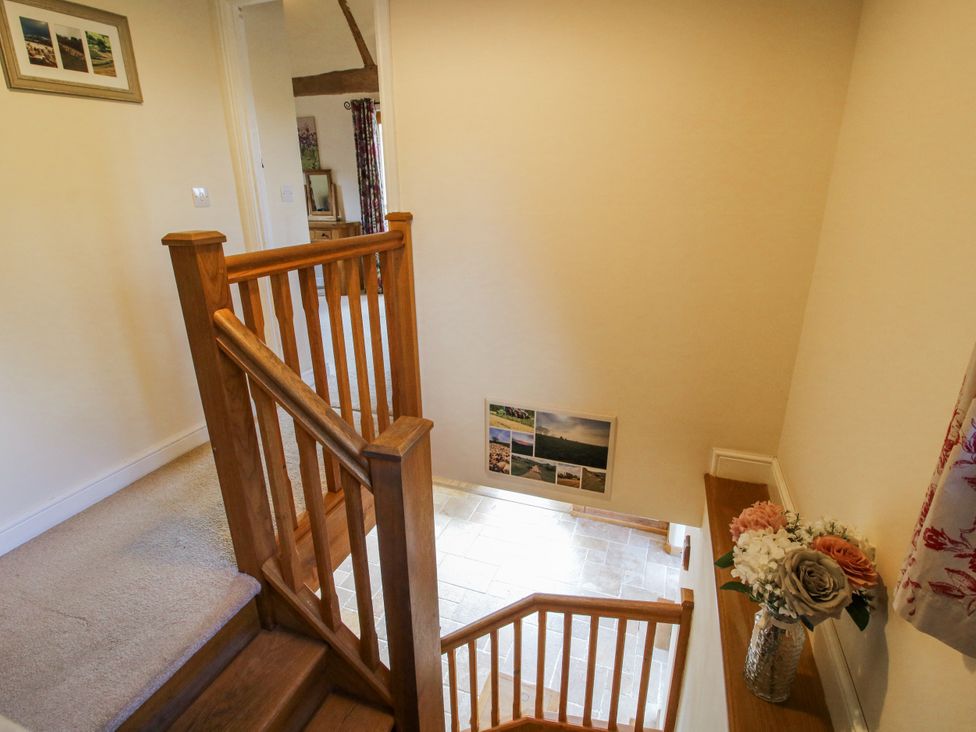 A staircase with a wooden railing in a hallway at The Hayloft Bleddfa near Knighton