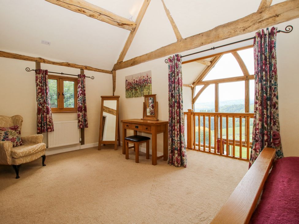 A bedroom with an armchair and dressing table at The Hayloft in Bleddfa near Knighton