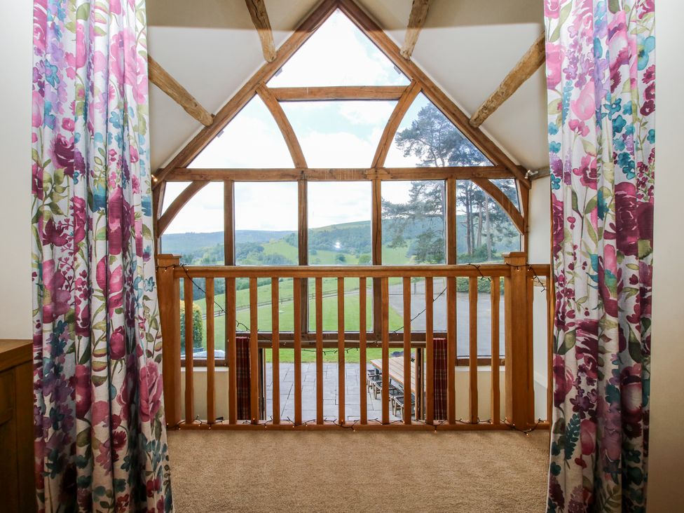 A balcony with wooden railing and curtains at The Hayloft in Bleddfa near Knighton