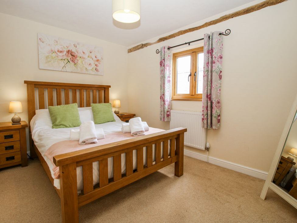 A bedroom with a wooden bed and floral decor at The Hayloft in Bleddfa near Knighton