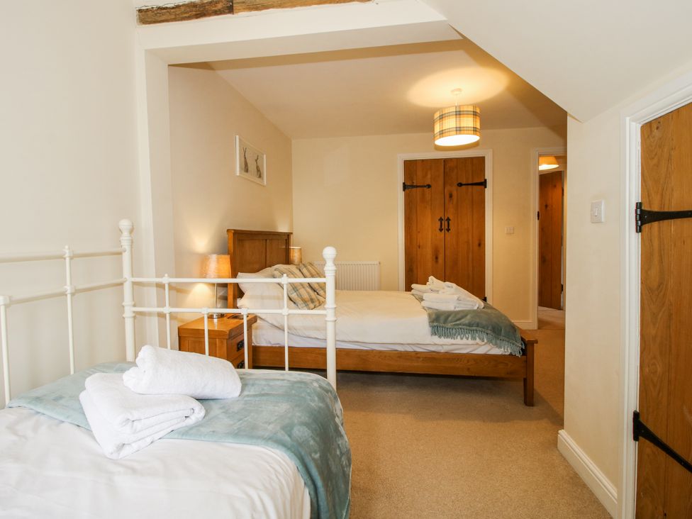 A bedroom with two beds and wooden furniture at The Hayloft in Bleddfa near Knighton