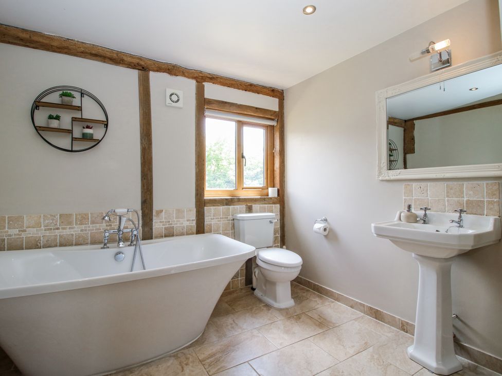 A bathroom with a bathtub, toilet, sink and mirror at The Hayloft in Bleddfa near Knighton