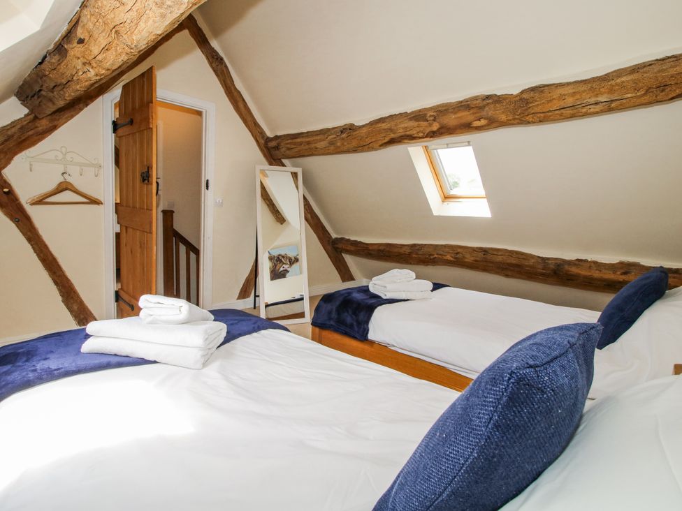 A bedroom with two beds and a mirror at The Hayloft in Bleddfa near Knighton