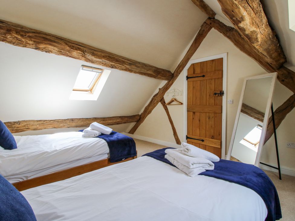 A bedroom with two beds and a mirror at The Hayloft in Bleddfa near Knighton