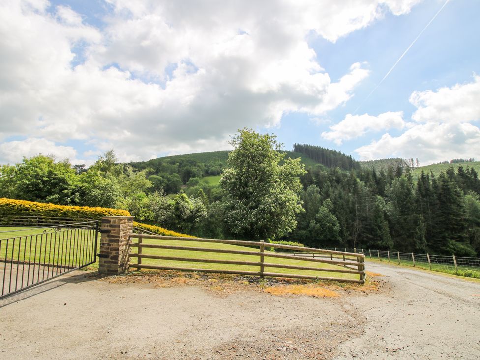 An outdoor scene with a gate and trees at The Hayloft in Bleddfa near Knighton