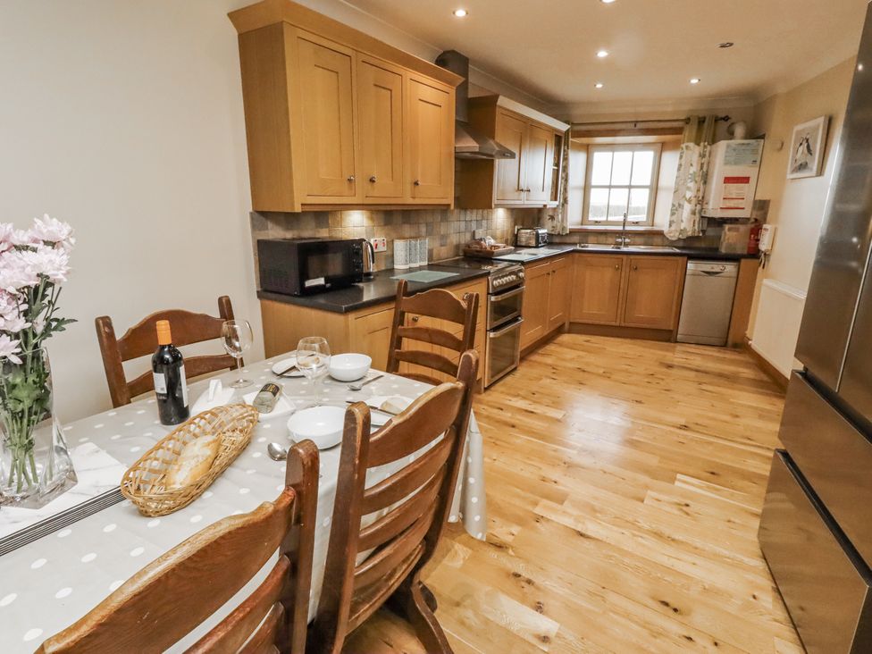 A kitchen with wooden cabinets and appliances at High Hemmel House in Embleton