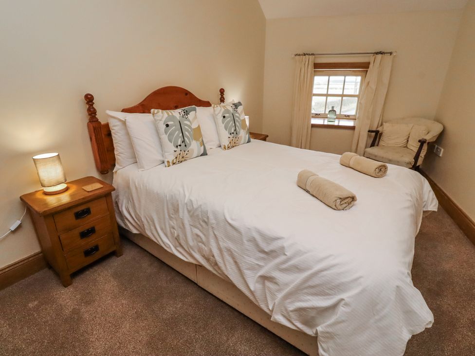 A bedroom with a bed and bedside table at High Hemmel House in Embleton