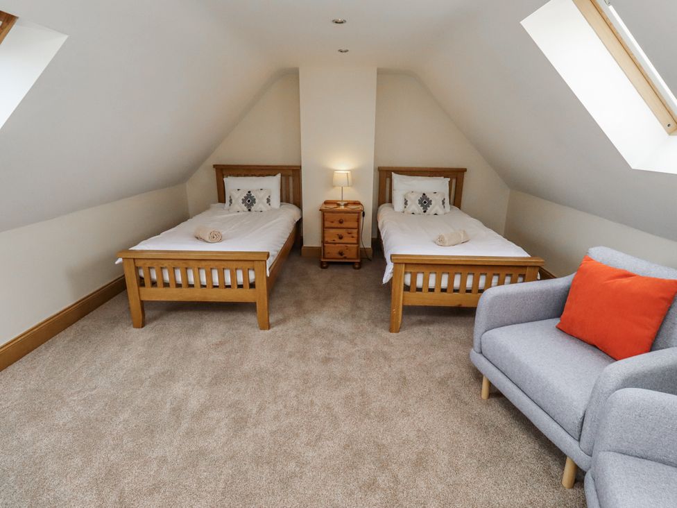 A bedroom with two beds and a nightstand at High Hemmel House in Embleton