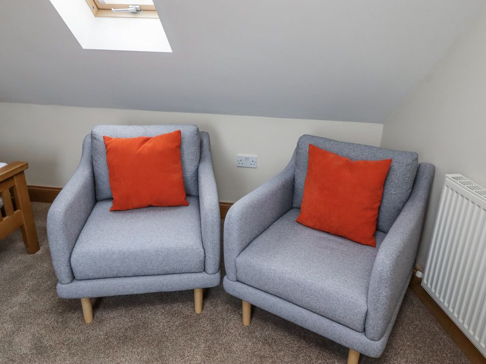 Two armchairs with orange cushions in a living room at High Hemmel House Embleton