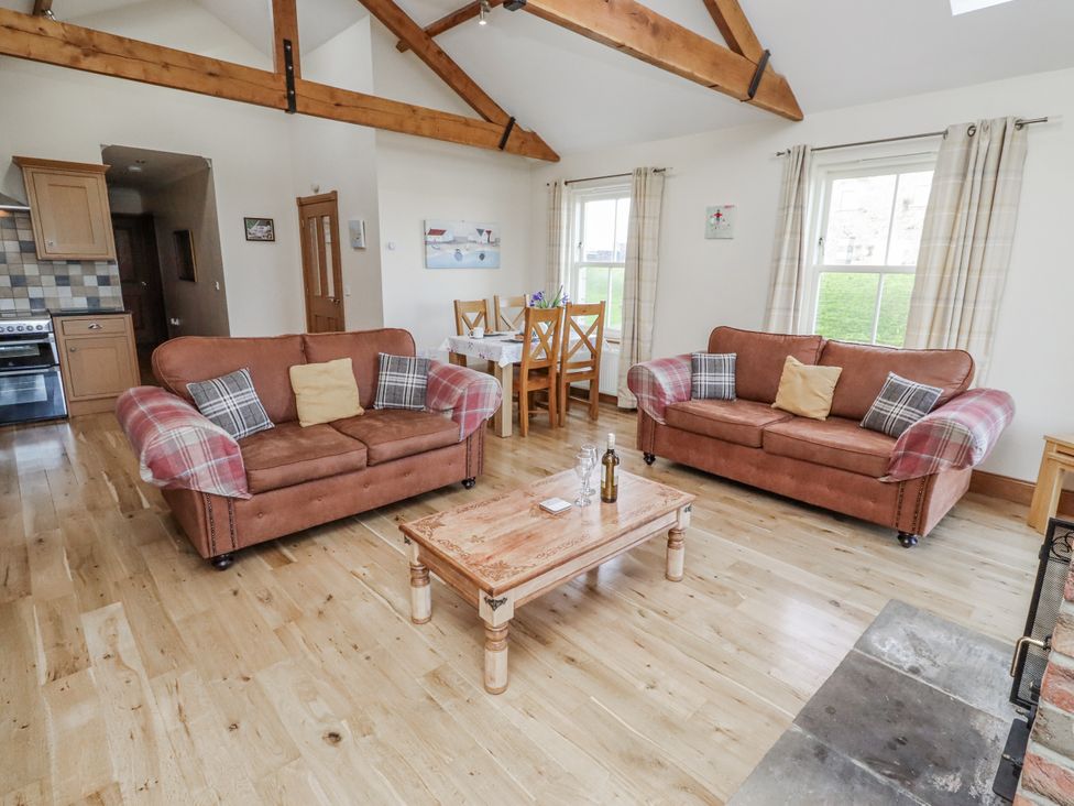 A living room with sofas and a wooden table at Home Stead Cottage in Embleton