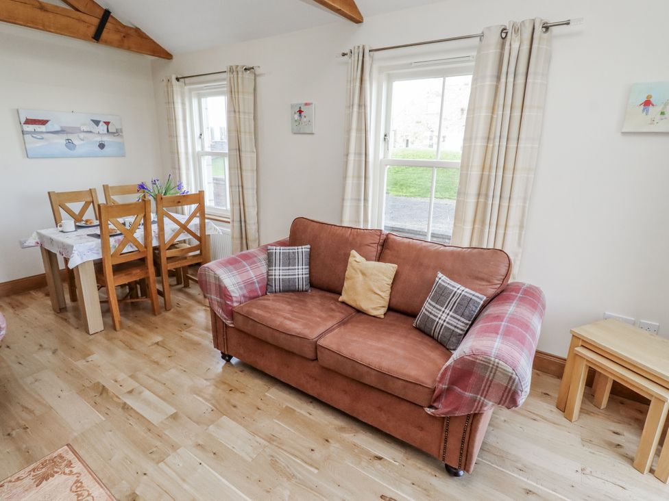 A living room with a sofa and dining area at Home Stead Cottage in Embleton