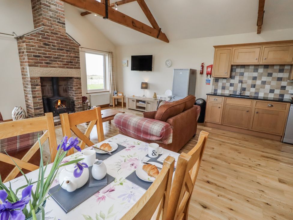 A living room with a fireplace and dining table at Home Stead Cottage in Embleton