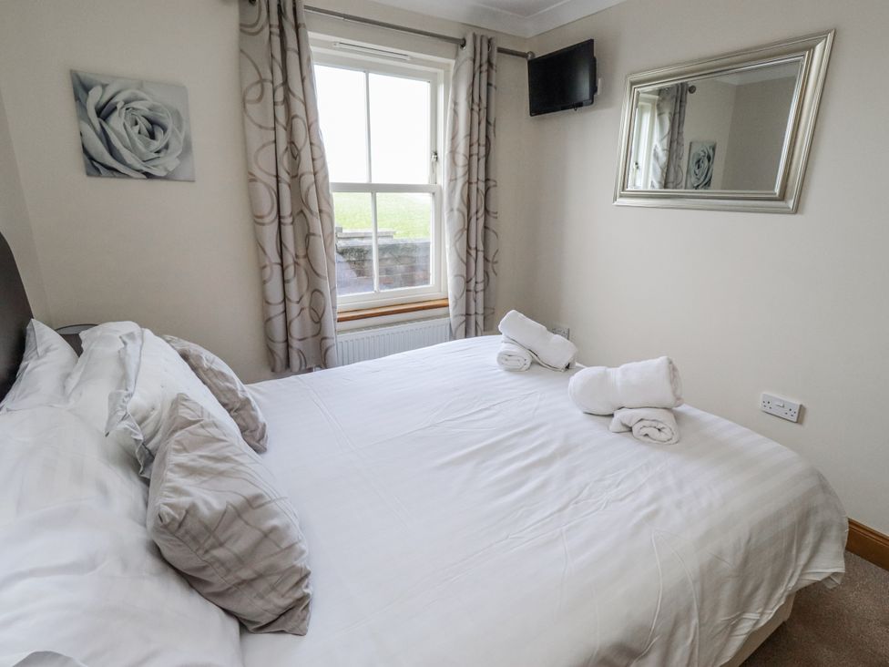 A bedroom with a bed and a mirror at Home Stead Cottage in Embleton