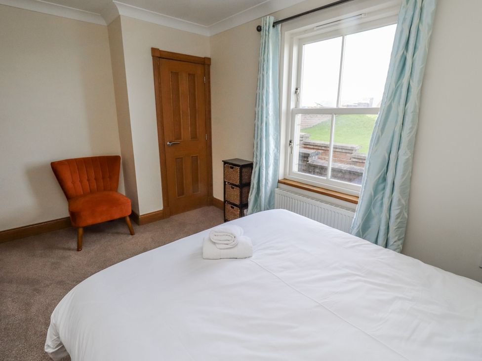 A bedroom with a bed, chair, and storage unit at Home Stead Cottage in Embleton