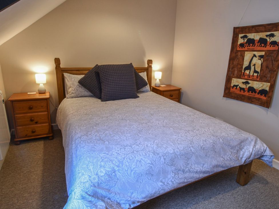 A bedroom with a bed and nightstands at Kingfisher in Blaenwaun