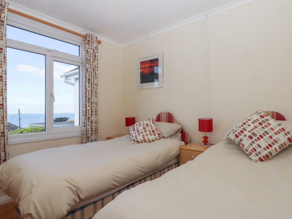 A bedroom with two beds and a window with a view at Highdown in Bigbury on Sea near Modbury