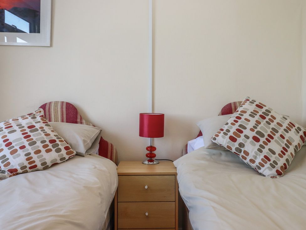 A bedroom with two beds and a bedside table in Highdown Bigbury on Sea near Modbury