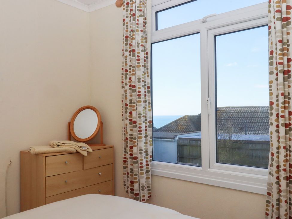 A bedroom with a window, a mirror, and a dresser at Highdown in Bigbury on Sea near Modbury